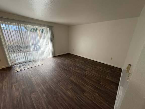 A room with wooden flooring and a window with blinds.