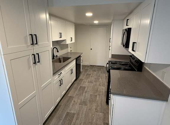 A kitchen with white cabinets and a black stove top oven.