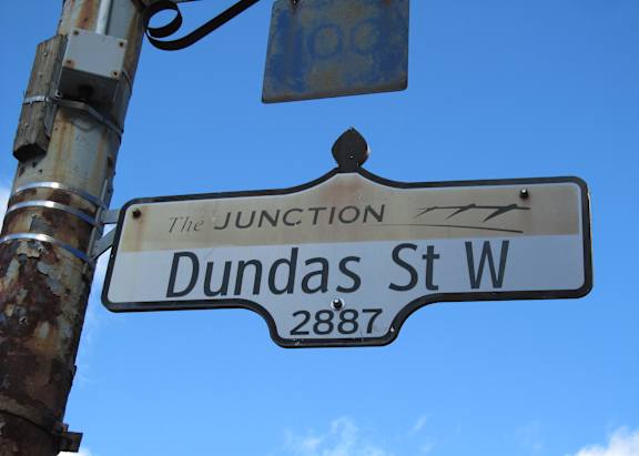 A street sign for Dundas St W is shown against a blue sky.