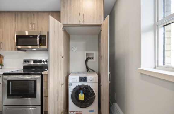 a small laundry room with wooden cabinets and a washer and dryer