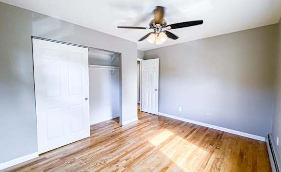A room with a ceiling fan and wooden floors.