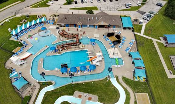 An aerial view of a water park with a large blue pool and a winding white path.