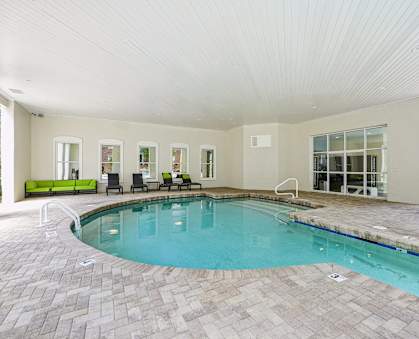A large indoor swimming pool with a tiled floor and a bench.