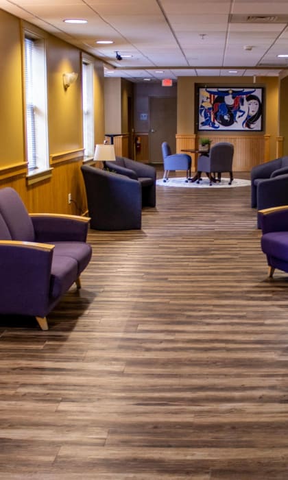a waiting room with blue chairs and a wooden floor