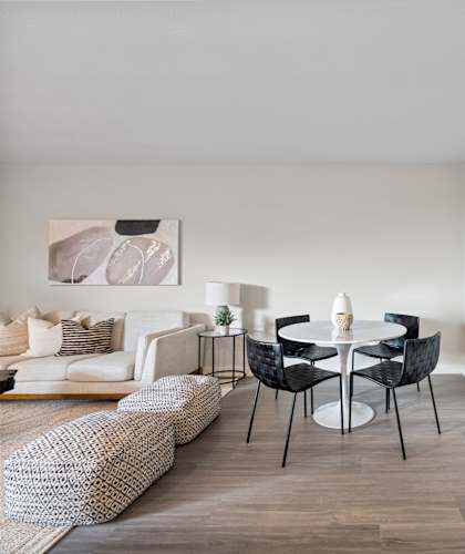a dining area with a round table and four black and white chairs