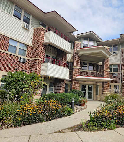 A multi-story apartment building with a landscaped courtyard in front.