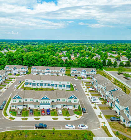 an aerial view of an apartment complex with parking lot and trees