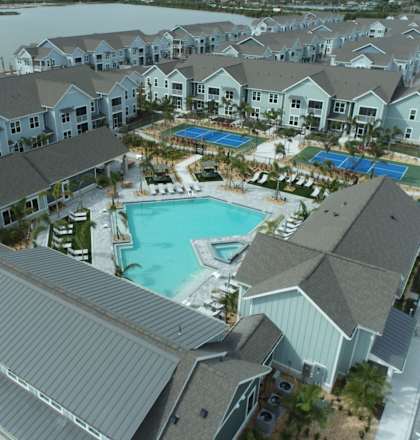 A large swimming pool is surrounded by a covered patio and a building.