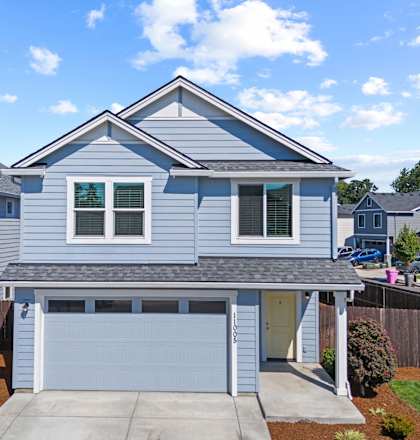 A house with a grey garage door and a brown driveway.