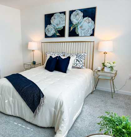 a bedroom with a white bed and two paintings on the wall