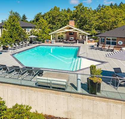 A large swimming pool surrounded by lounge chairs and umbrellas.