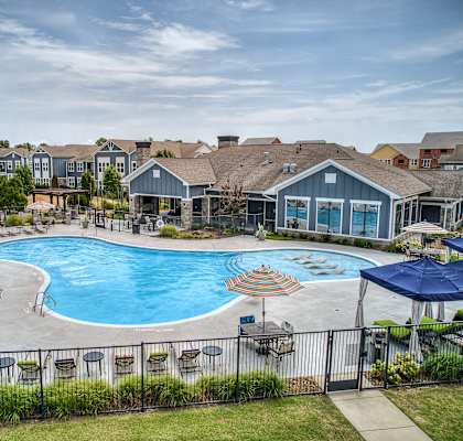 A large swimming pool surrounded by a fence and chairs.