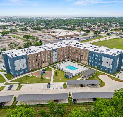 A large apartment complex with a swimming pool in the middle.