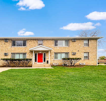 A brick building with a red door and windows.