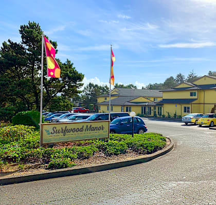 The Surfwood Manor sign is in front of a parking lot.