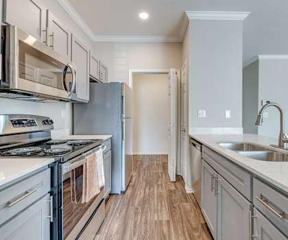 A modern kitchen with stainless steel appliances and wooden flooring.