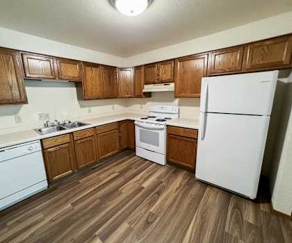 an empty kitchen with white appliances and wooden cabinets