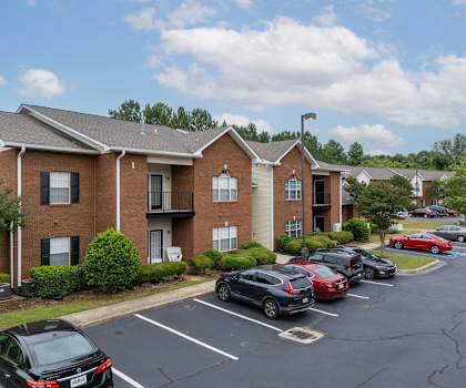 a parking lot in front of a brick apartment building with cars parked in front