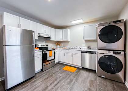 a kitchen with white cabinets and appliances and a stainless steel refrigerator