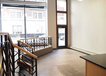 A view of a staircase with a black railing and wooden handrails.