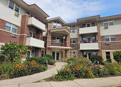 A multi-story apartment building with a landscaped front yard.