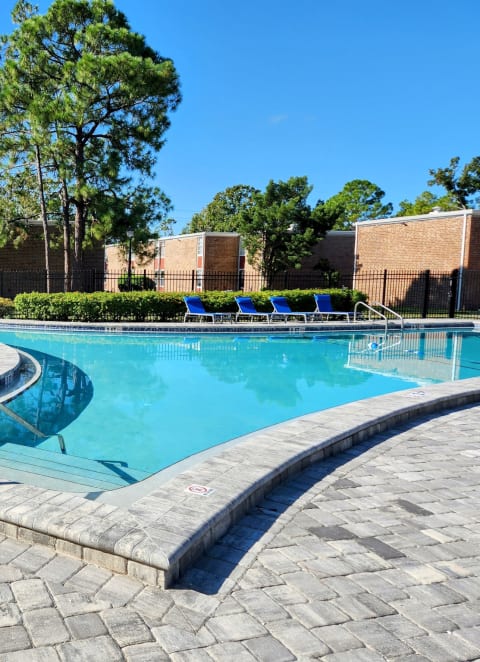 a pool deck area with with a table and chairs at Timberfalls Apartments
