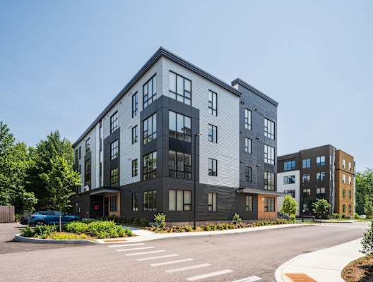 A modern multi-story building with a parking lot in front.