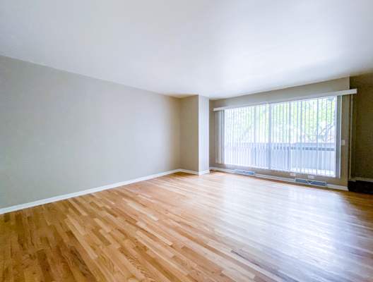 A room with wooden flooring and a sliding glass door.