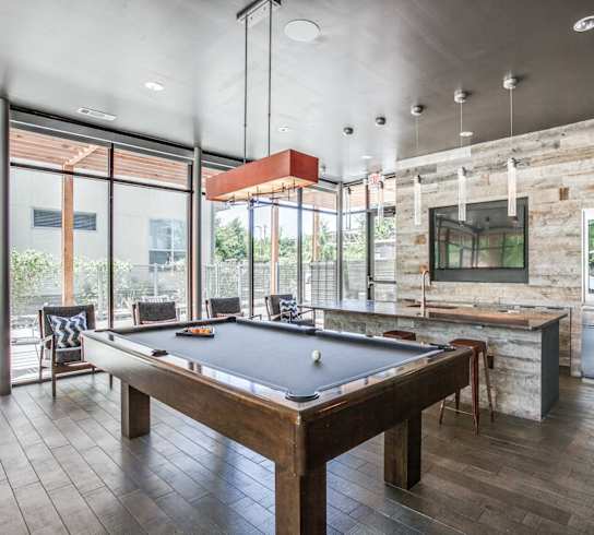 A pool table in a room with a stone wall and a bar.