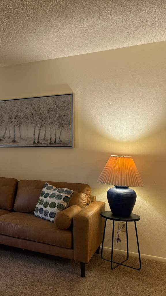 A living room with a brown couch, a chair, a coffee table, and two lamps.