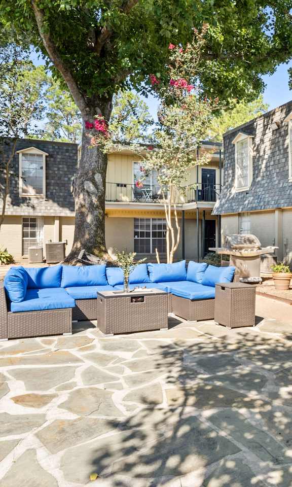 A patio with a stone floor and a blue couch.
