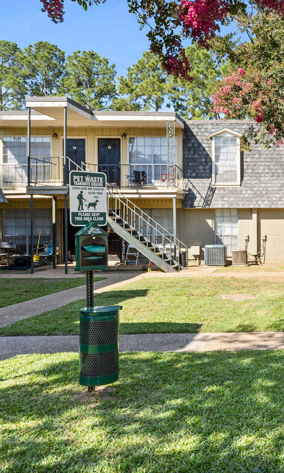 A sunny day at a residential complex with a green lawn and apartment buildings.