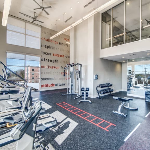a gym with weights and cardio equipment in a building with large windows