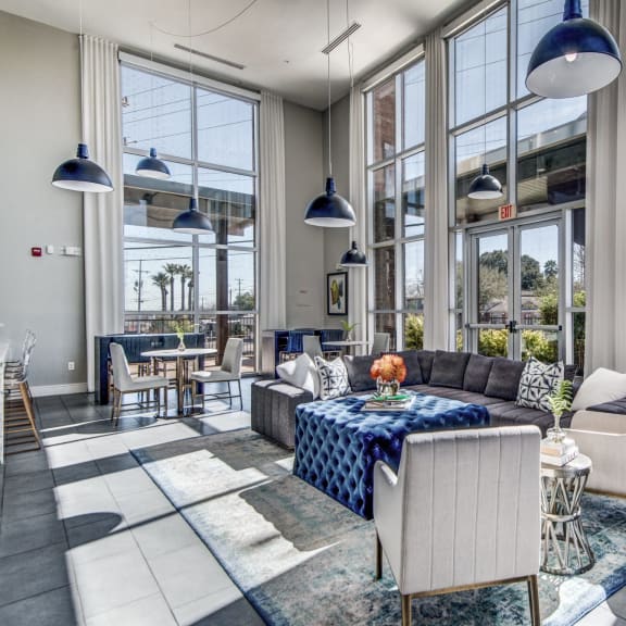 a living room with large windows and a table with a couch and chairs