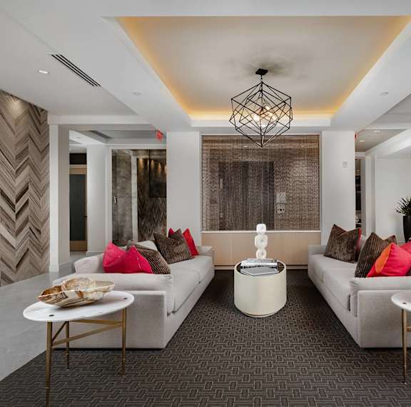 A modern living room with a grey carpet and a white sofa.