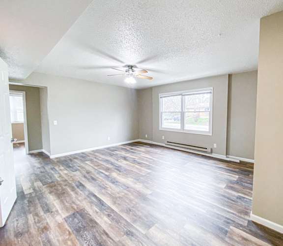 an empty living room with a ceiling fan and a window
