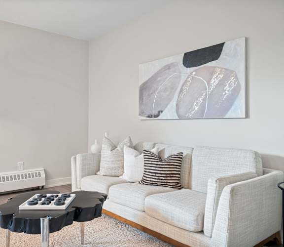 a living room with a white couch and a black and white painting on the wall