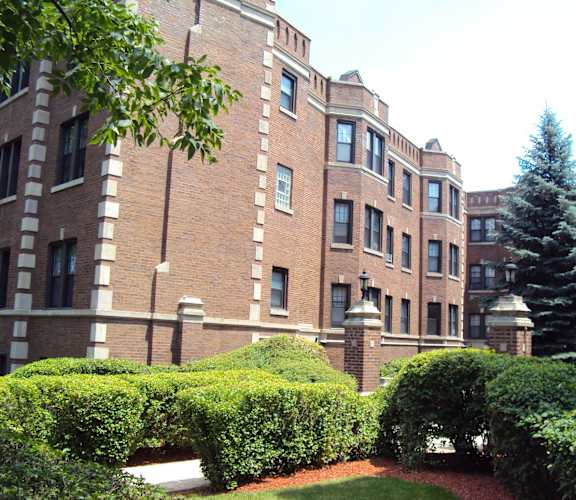 A large brick building with a tree in front of it.