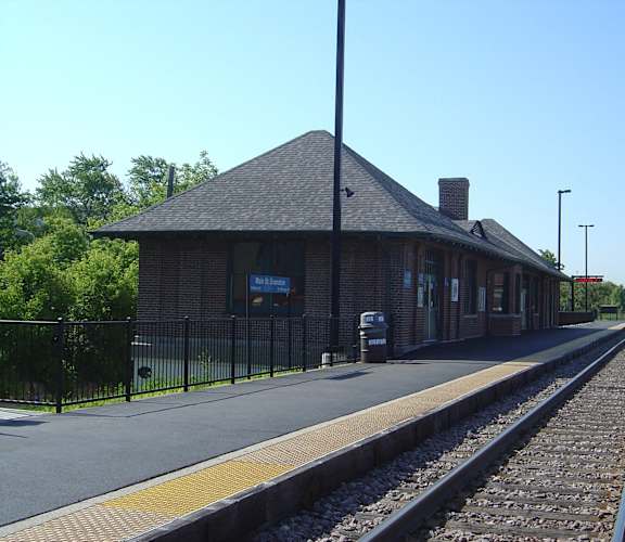 A train station with a brick building and a train on the tracks.