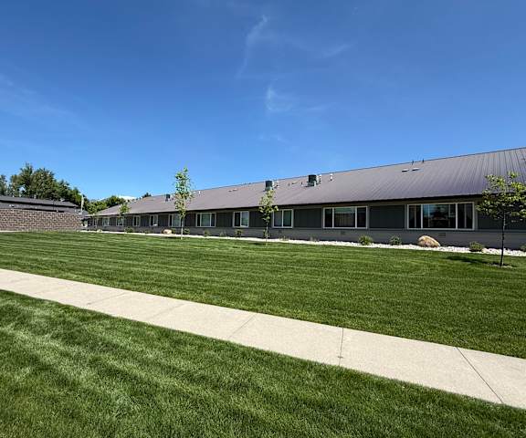 A building with a grey roof and a green lawn in front.