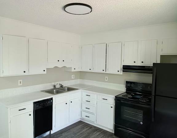 an empty kitchen with white cabinets and black appliances