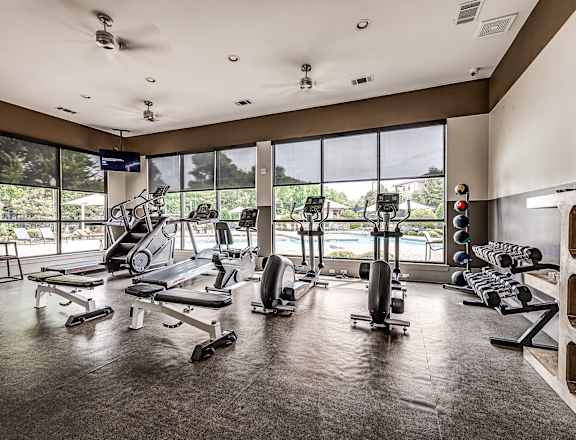 A gym with a variety of equipment including treadmills, weights, and exercise machines.
