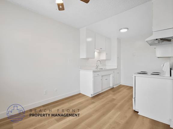 A kitchen with white cabinets and a wooden floor.