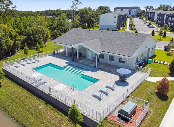 an aerial view of a house with a swimming pool and patio furniture