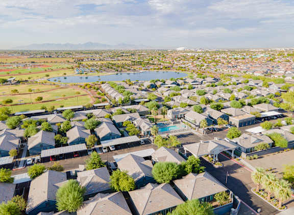 an aerial view of a neighborhood with many houses and a pond at Villas on Olive in Peoria, AZ 85345