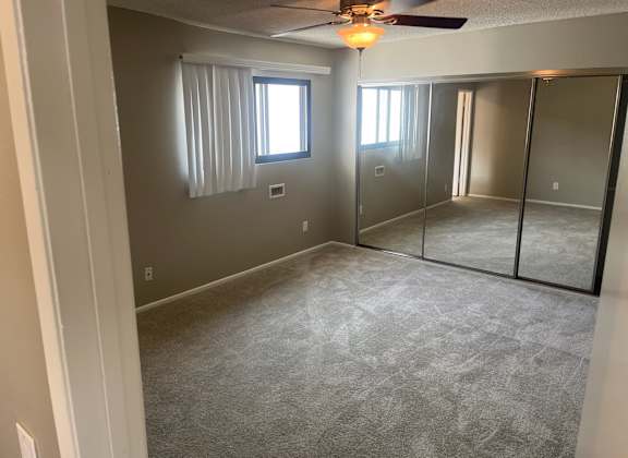 A room with a ceiling fan and a window with blinds.
