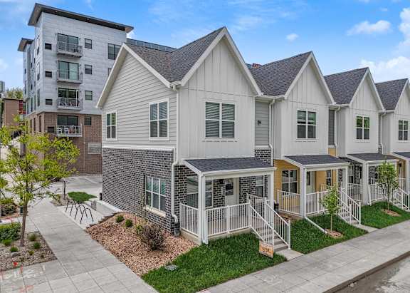 A row of houses with a sidewalk and a tree in front of them.at Soll, Des Moines Iowa