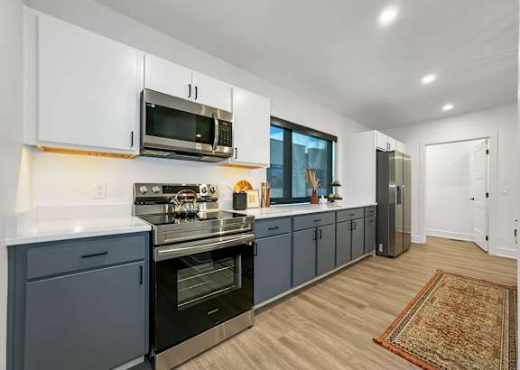 a kitchen with blue cabinets and a stove and a microwave at Matilda 235 Townhomes, Des Moines, 50309
