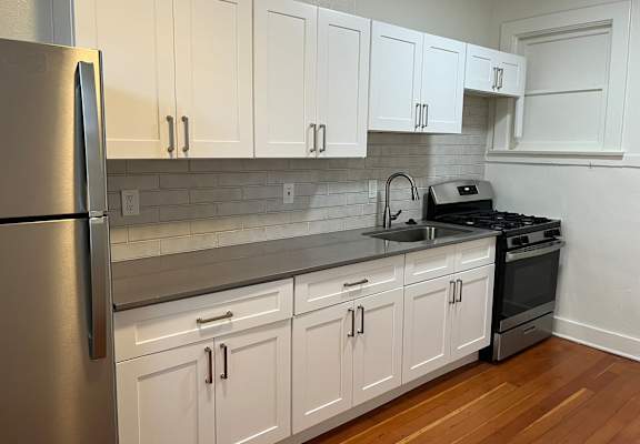 a kitchen with white cabinets and a sink and a refrigerator