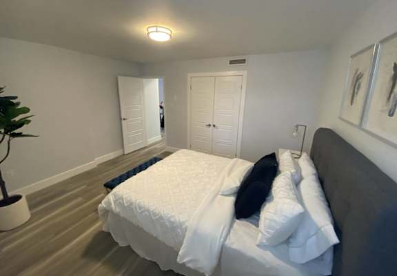A bedroom with a bed, pillows, and a plant.